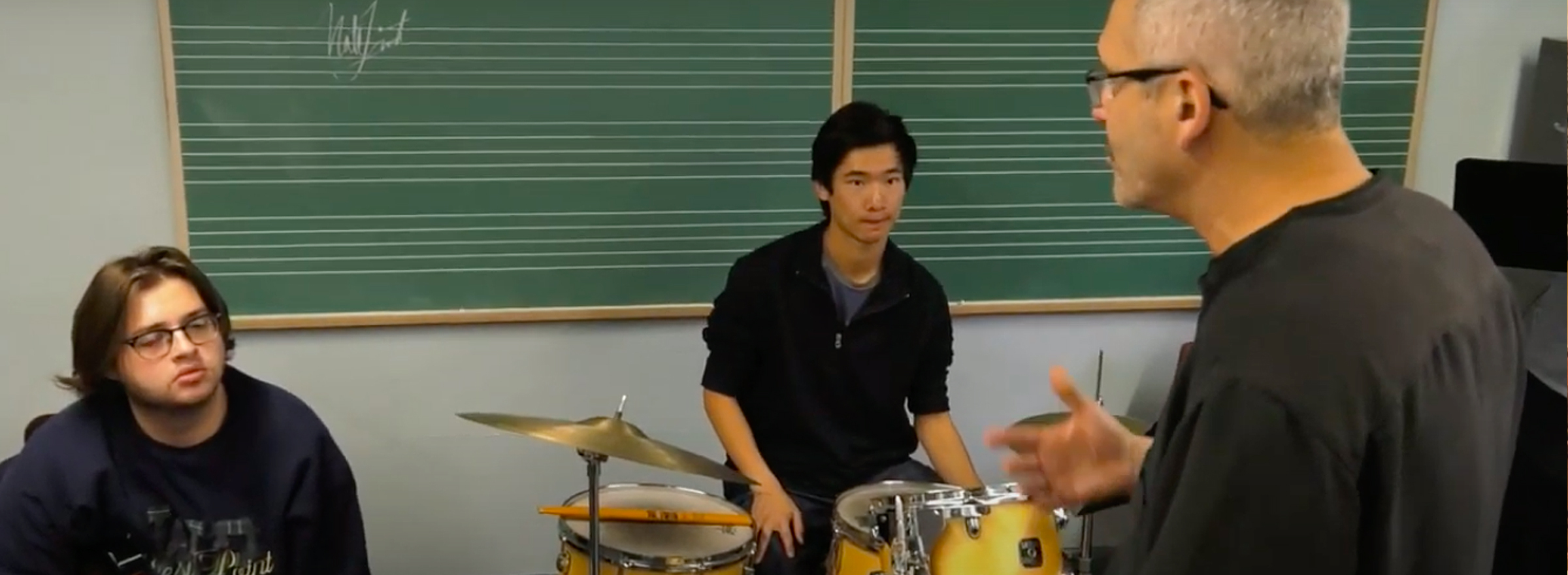 students in a classroom with a drum set