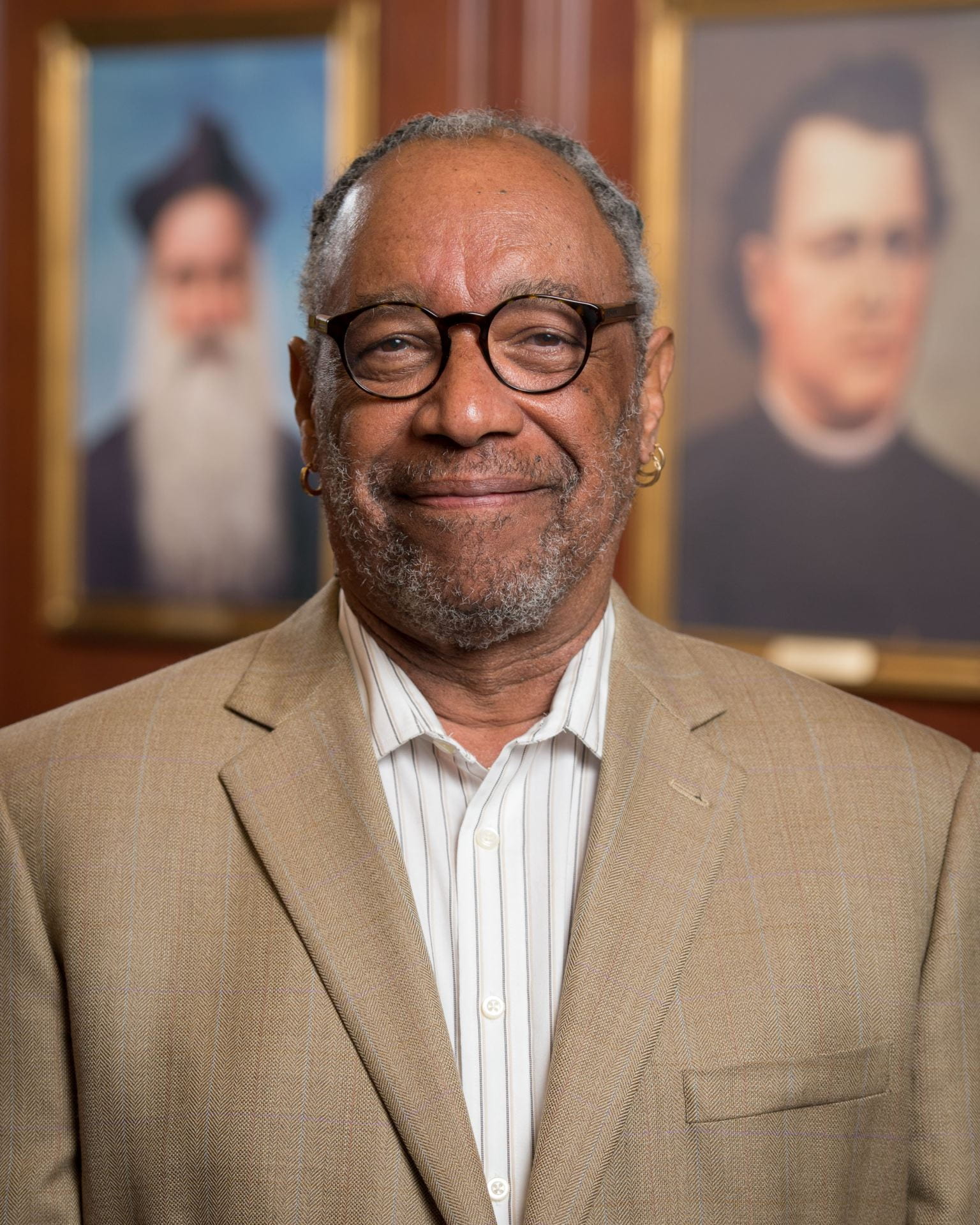 man with glasses standing in front of library stacks