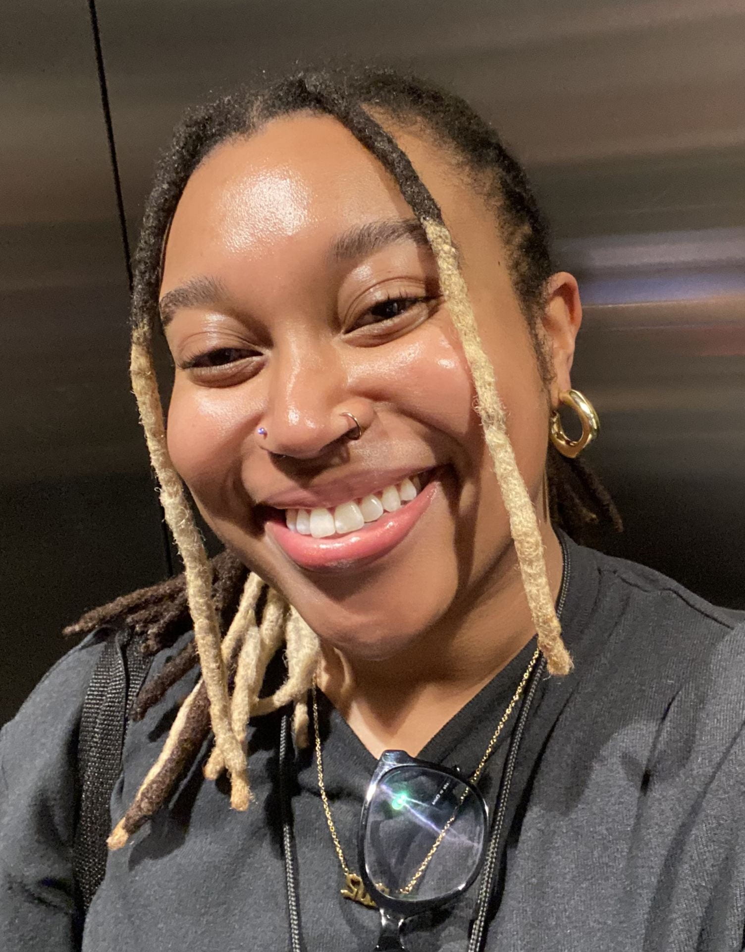 a smiling young woman with blond dreads.