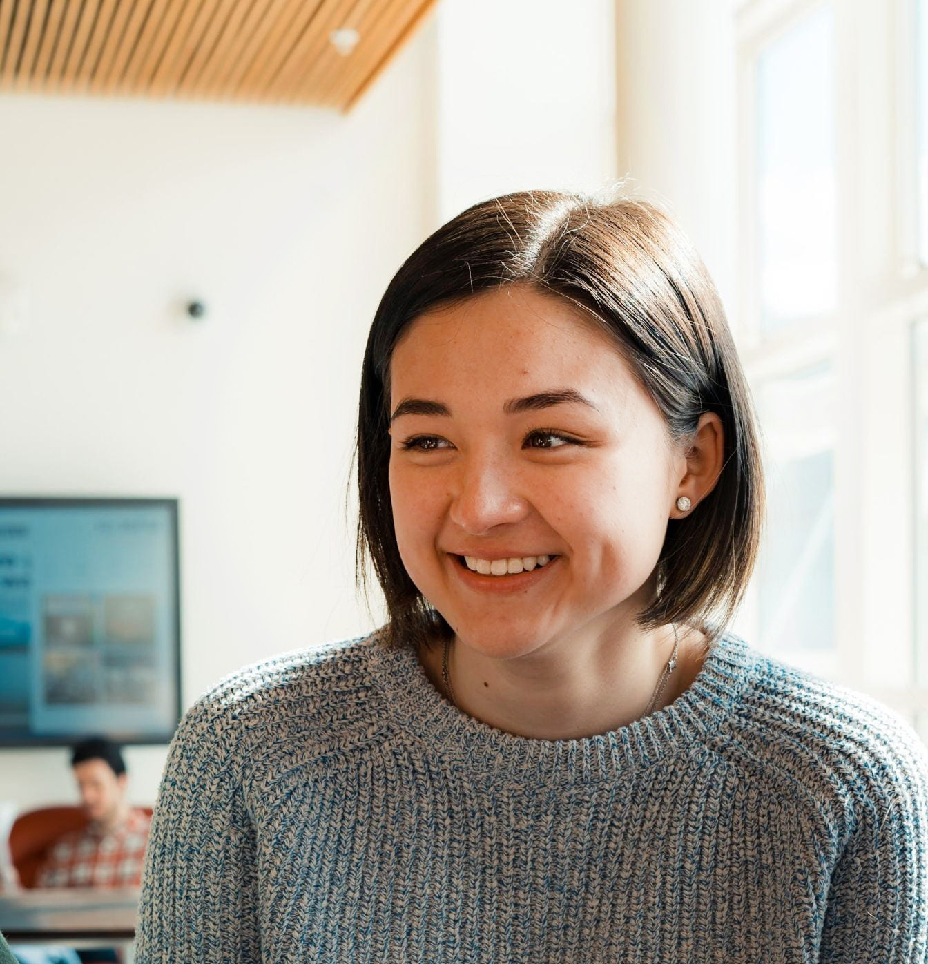 person with short brown hair and blue/gray sweater