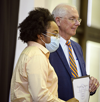 Student standing with President Christian for a photo with award