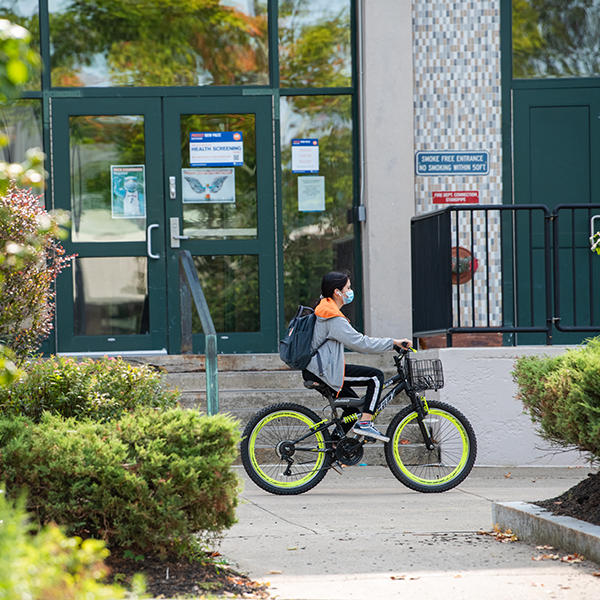 masked student on bike