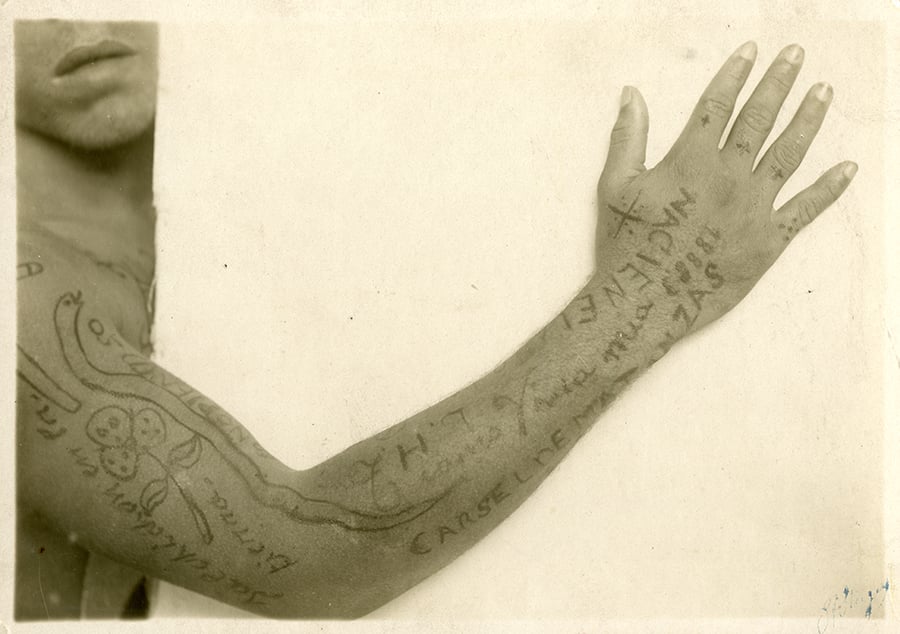 Prisoner having his tattoos photographed