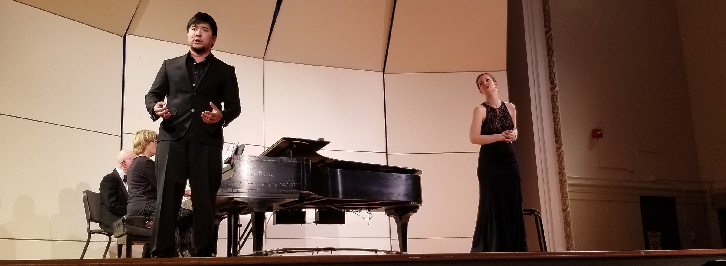 students performing on stage by a piano